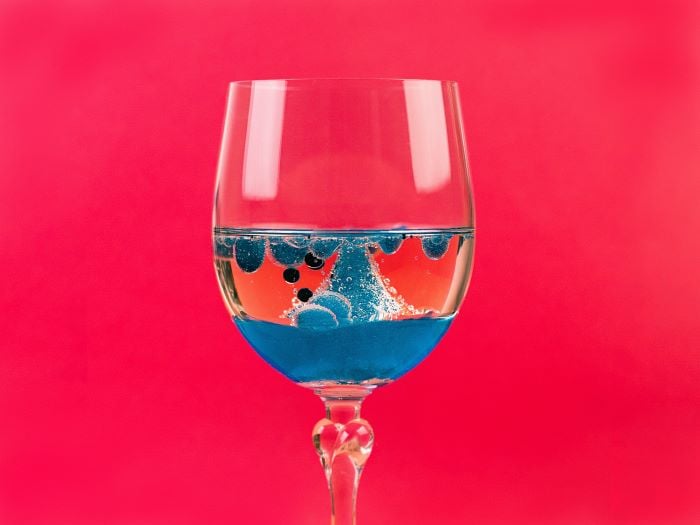 Striking image of a glass with blue liquid on a red background