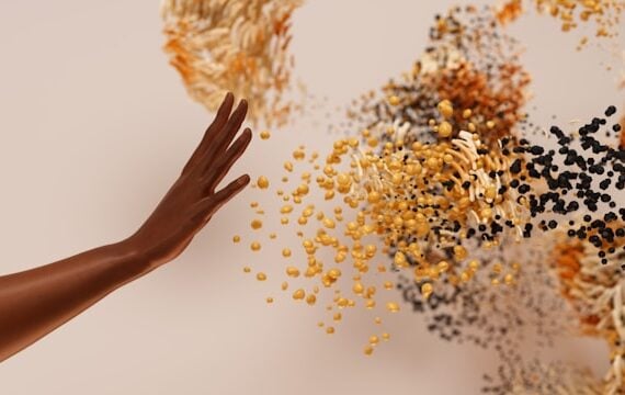 A hand extended to various coloured particles