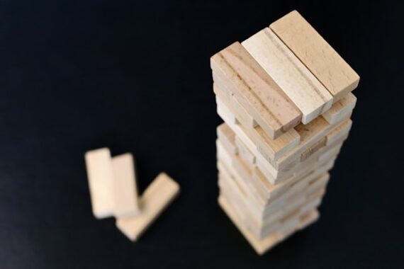 a high angle image of wooden Jenga blocks stacked up on a black background. 3 spare blocks on the side of the stack