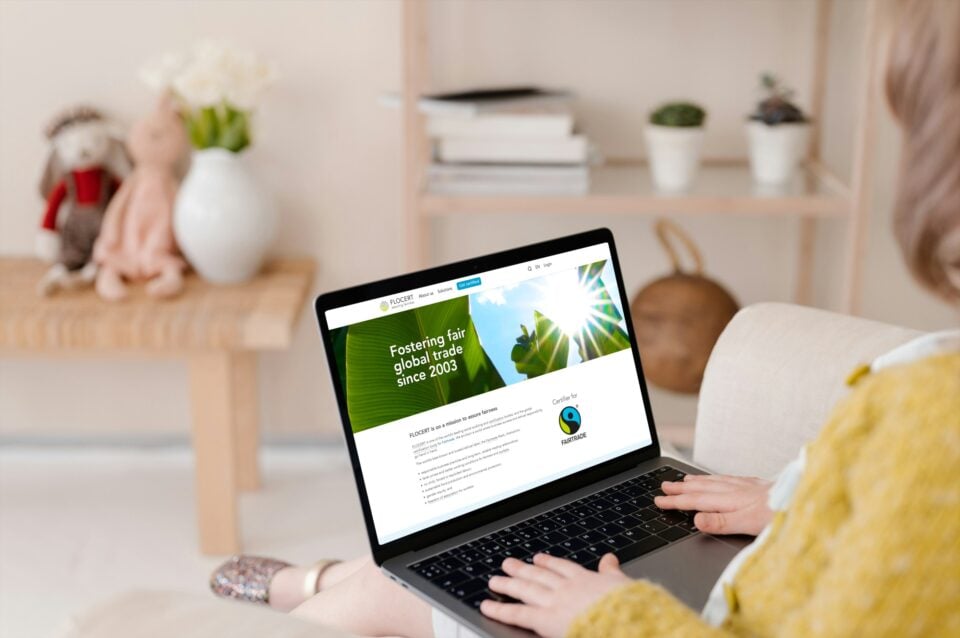 A woman sat on a sofa with a laptop on her knees displaying FLOCERT website